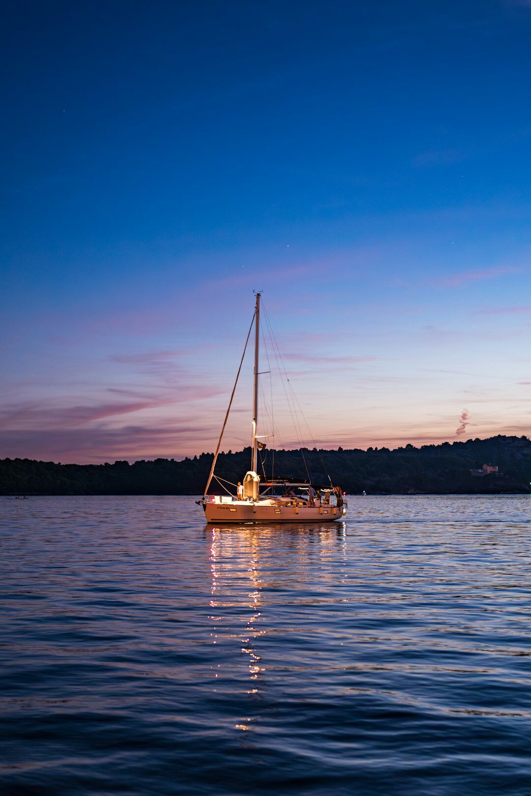White sailing yacht anchored near the coast at dusk